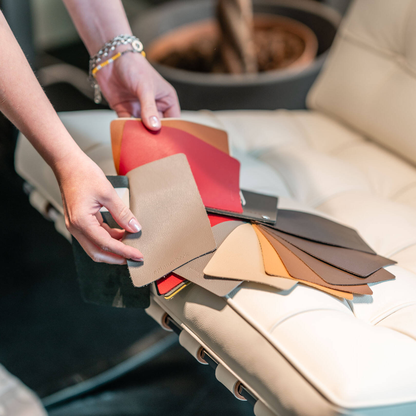 Lederproben in verschiedenen Farben auf einer cremefarbenen Lederliege bei der Materialberatung