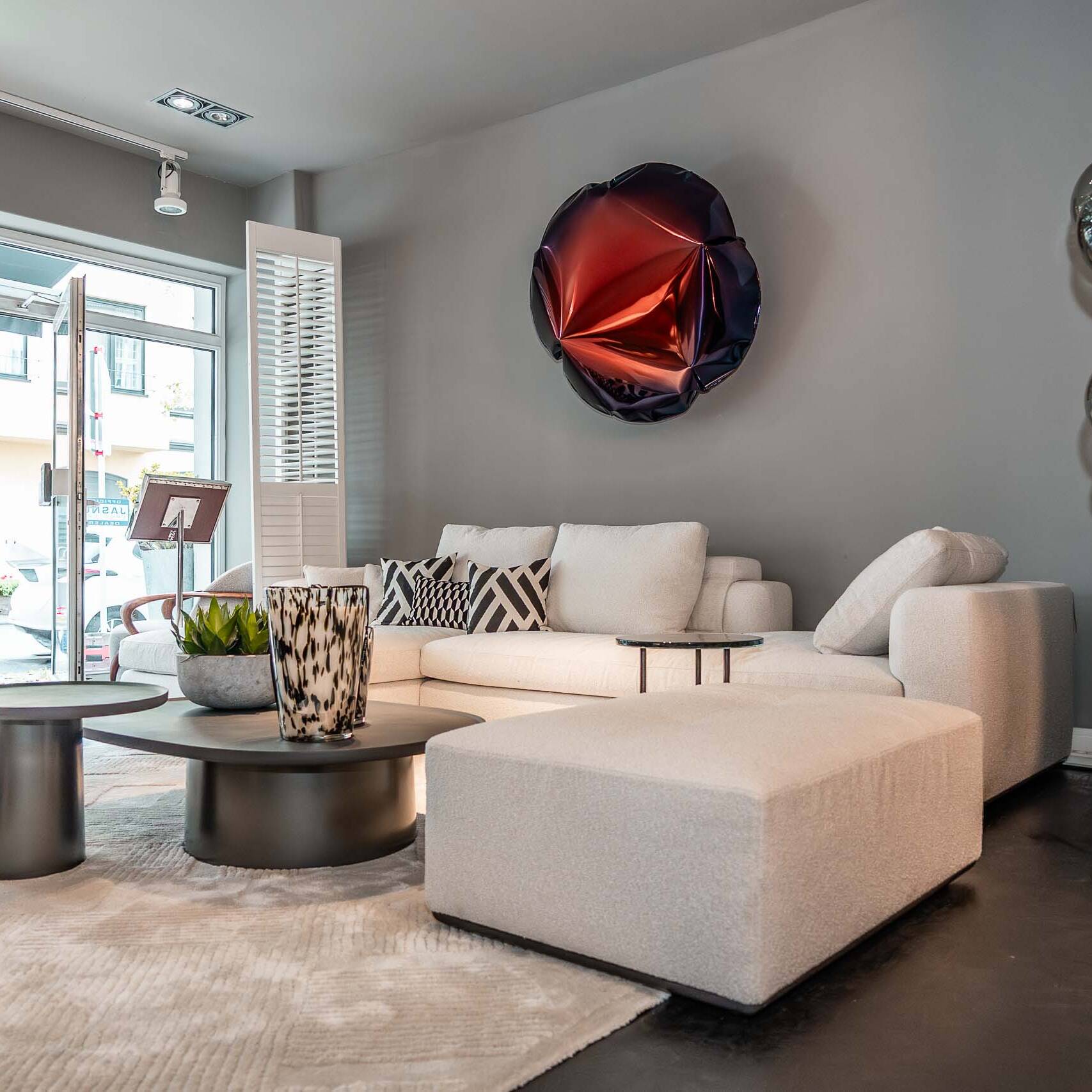 Wohnbereich im Showroom Düsseldorf-Oberkassel mit weißem Ecksofa, runden Couchtischen und Kugel-Stehleuchte