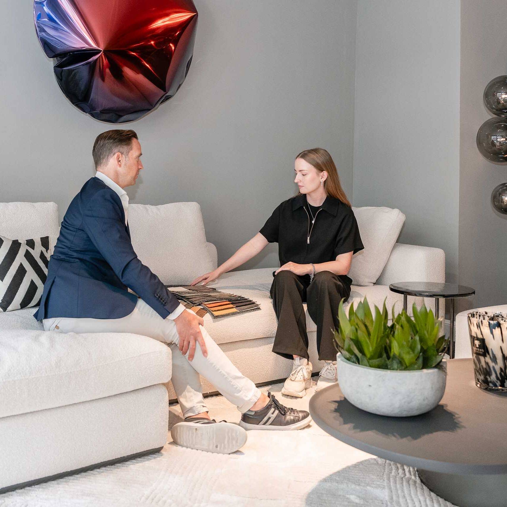 Beratungsgespräch mit Materialmustern auf einem weißen Sofa im Showroom Düsseldorf-Oberkassel