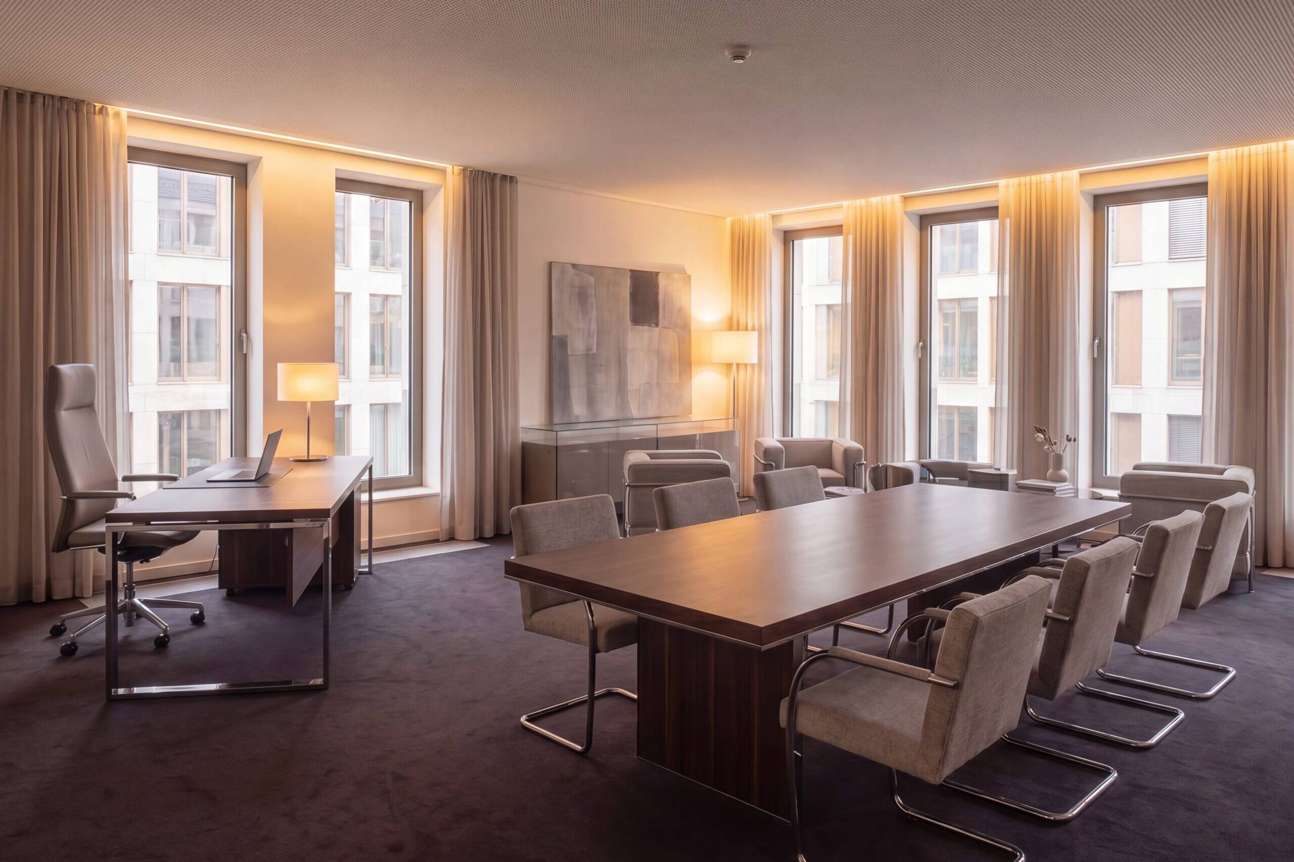Büro mit Konferenztisch, Arbeitsplatz und Fensterfront