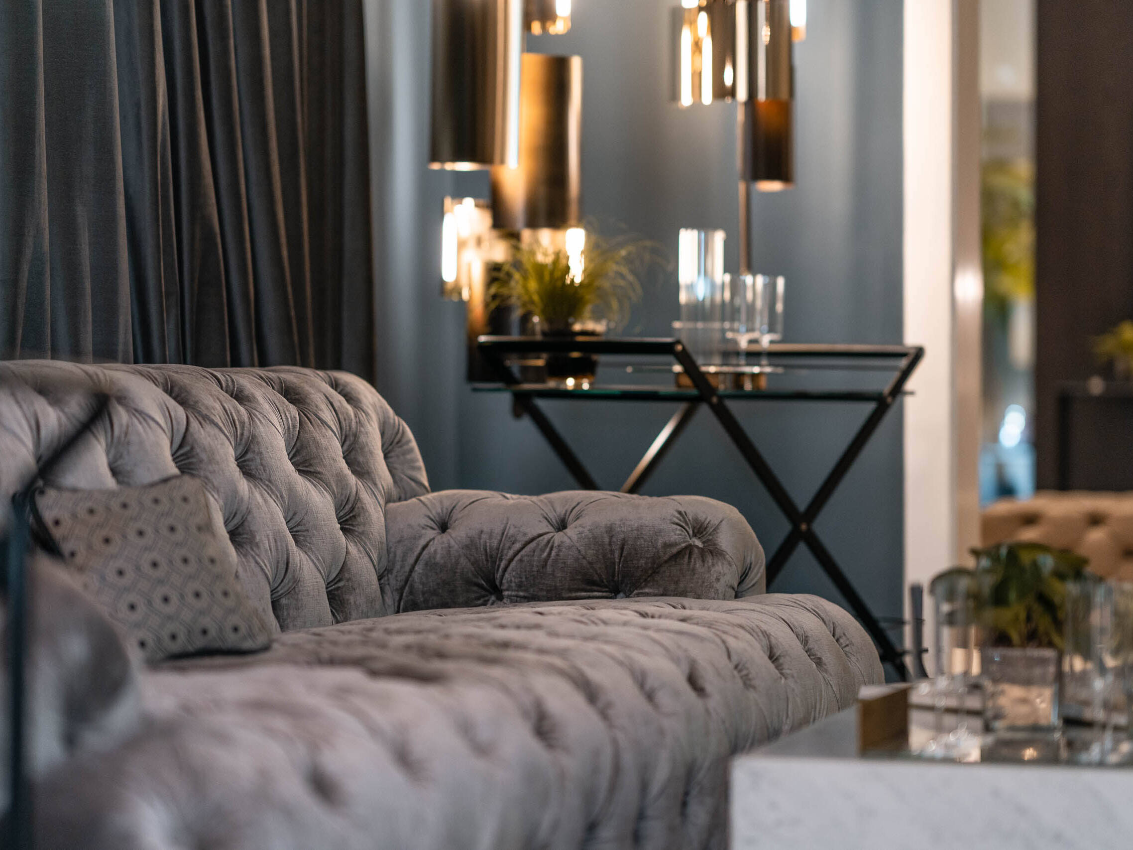 Chesterfield-Sofa aus grauem Samt mit Glas-Beistelltisch und Pendelleuchten im Showroom Oberkassel